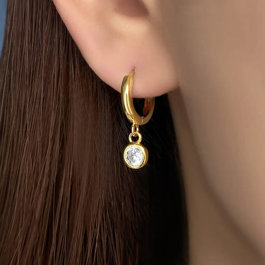 Gold hoop earring with a small round gemstone worn by a person with brown hair. Goldess Jewelley demi fine 18 k gold plated pvd
