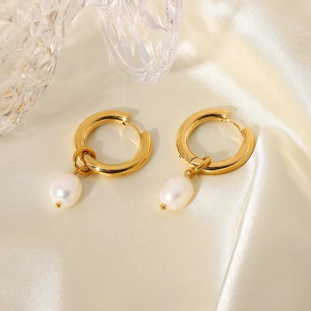 Gold hoop earrings with pearls on a white surface