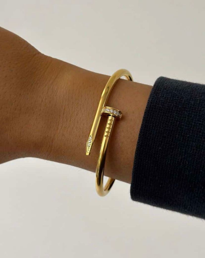Gold bangles on a wrist with a neutral background
