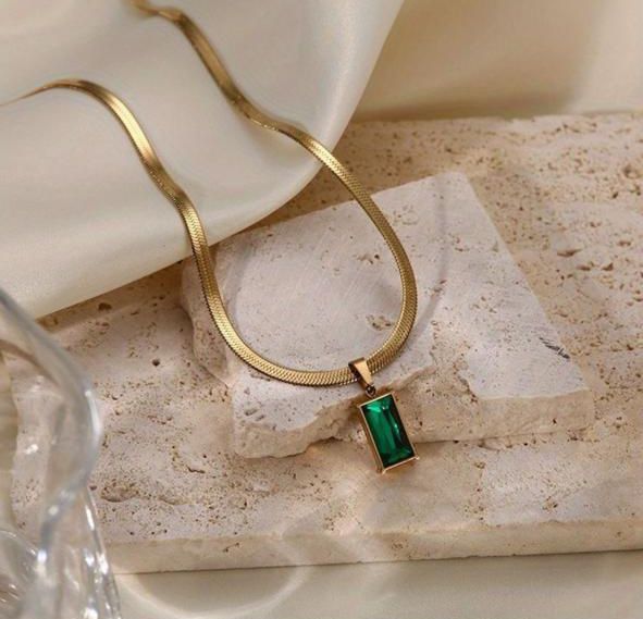 Gold necklace with a green pendant on a textured surface Goldess Jewellry 18k pure gold plating chain with pvd technology