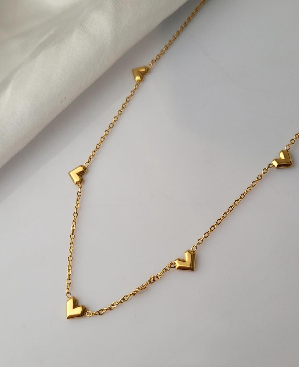 Gold necklace with heart-shaped pendants on a light gray backgroundGoldess Jewellry with pvd plating technology which last 10 times than normal jewelley 22