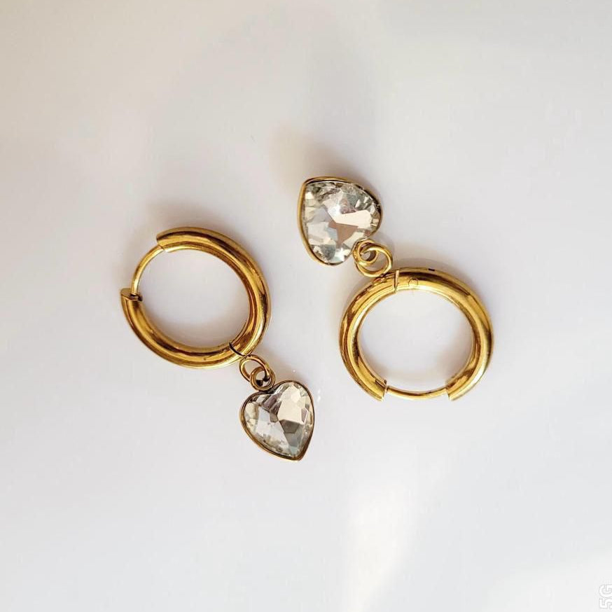 Gold hoop earrings with heart-shaped gemstones on a white background