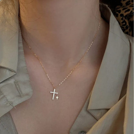 Necklace with a cross pendant worn by a person in a beige jacket. Goldess jewelley necklace 18k pure gold plating