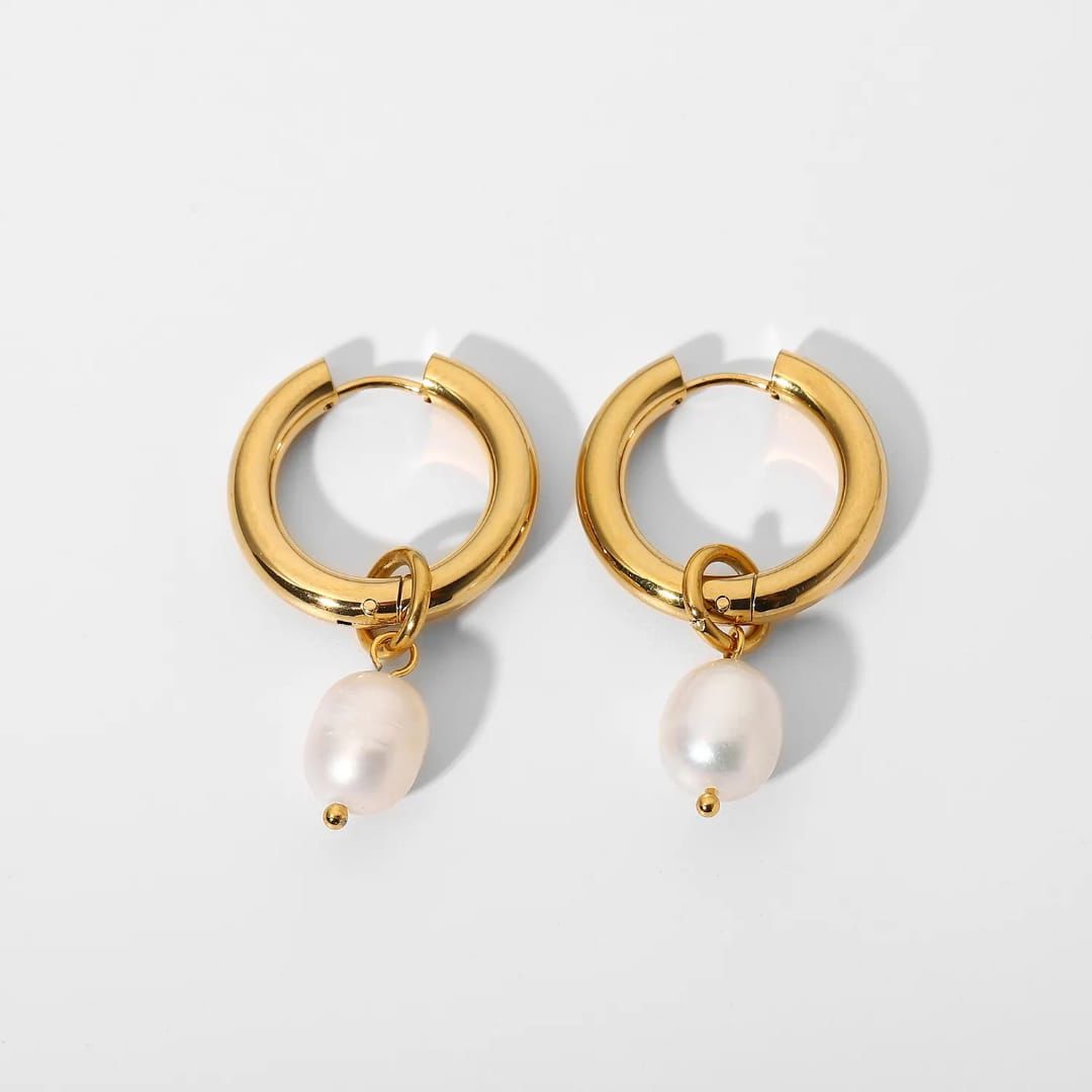 Gold hoop earrings with pearl drops on a light gray background