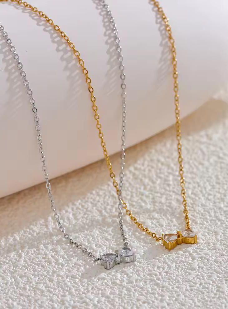 Two necklaces, one silver and one gold, on a textured surface.goldess jewellery 18k gold plated pvd technlogy
