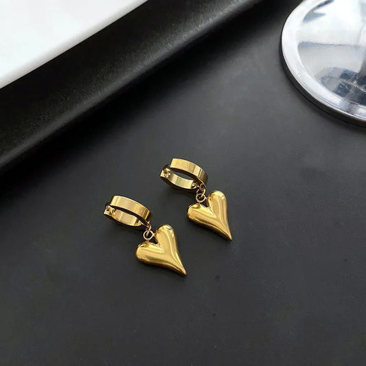 Gold heart-shaped earrings on a dark surface pvd gold plated goldess jewellry
