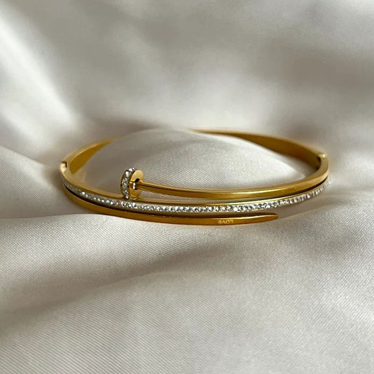 Gold bracelet with diamond accents on a white fabric background