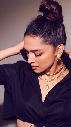 Woman wearing gold necklaces and earrings against a neutral  GOldes jewellry demi fine fation jewellrybackground