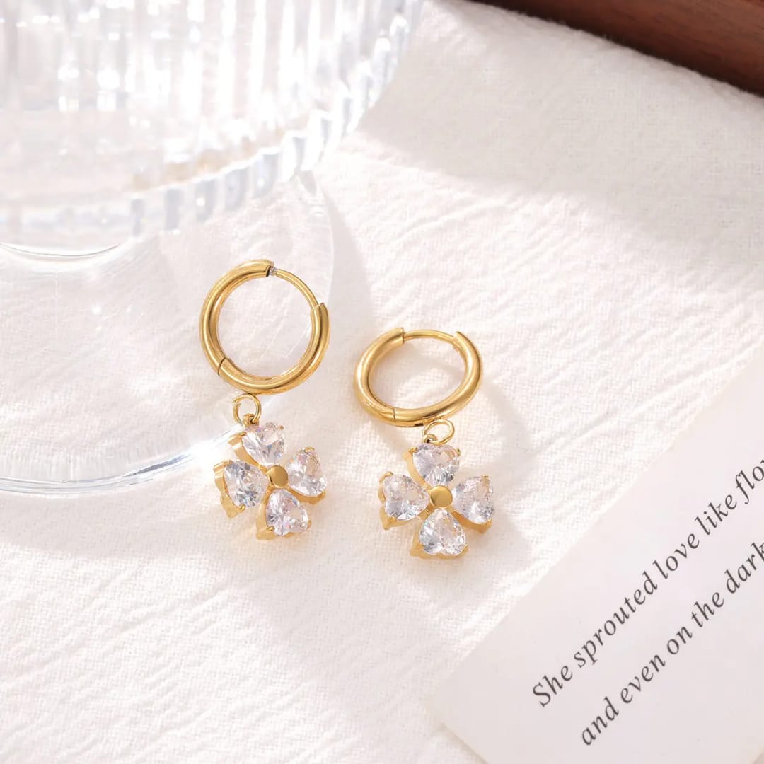 Gold hoop earrings with floral charms on a textured white surface. Gold_plated_earring_anti_tarnish goldess jewelley