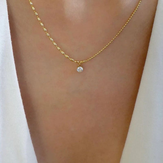 Gold necklace with a small diamond pendant on a person's neck against a white background Goldess Jewellery gold plated jewelley with pvd technology