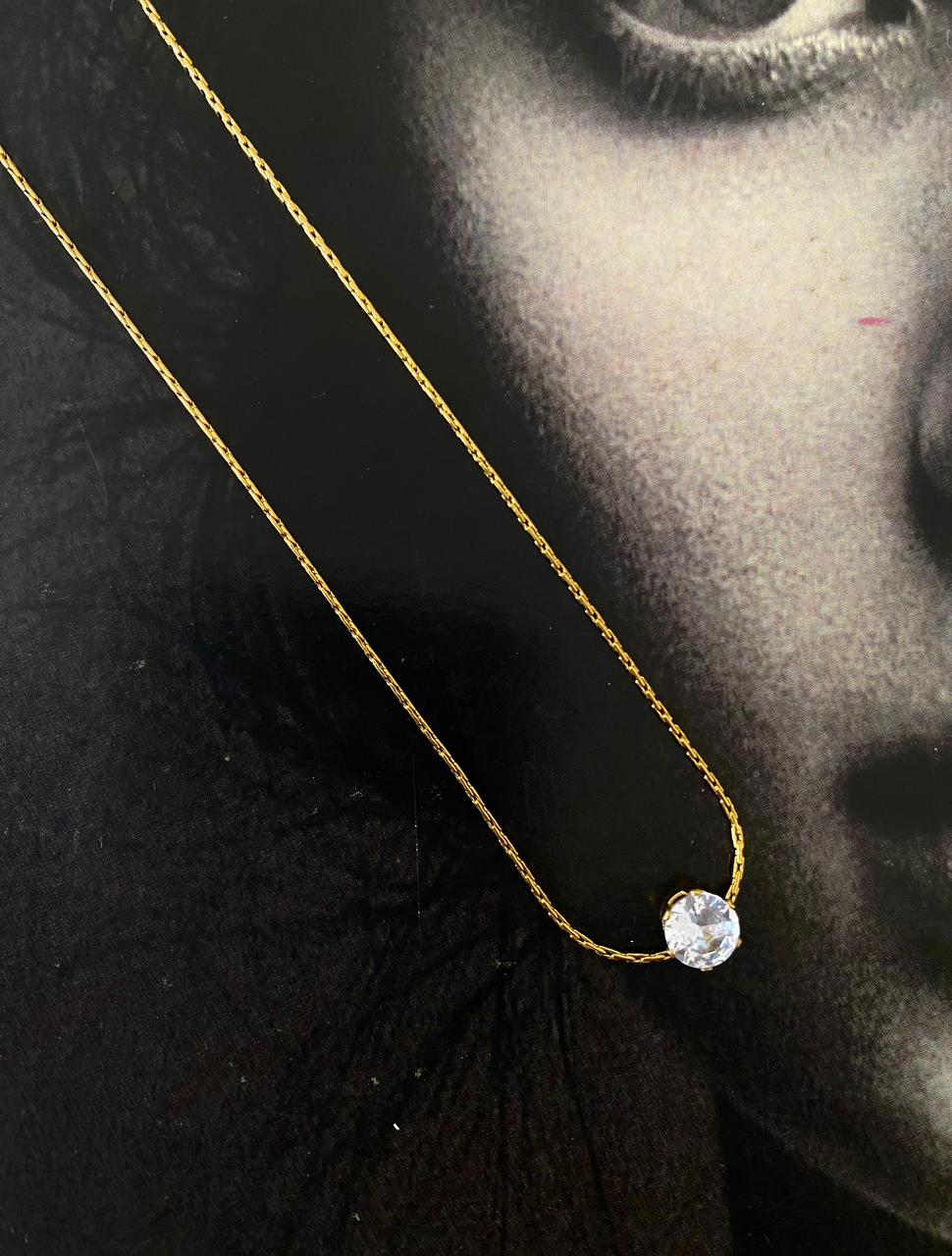 Gold necklace with a diamond pendant on a black background Goldess Jewellery gold plated jewelley with pvd technology