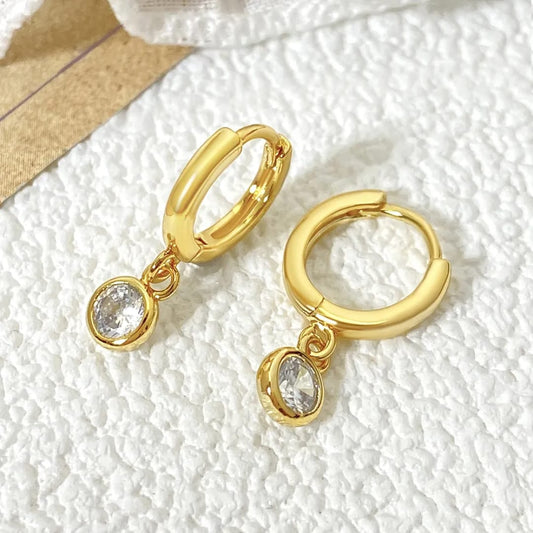 Gold hoop earrings with crystal drops on a textured white surface Goldess Jewelley demi fine 18 k gold plated pvd