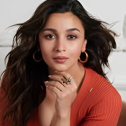 Woman wearing a red sweater with hoop earrings and a ring, sitting indoors.