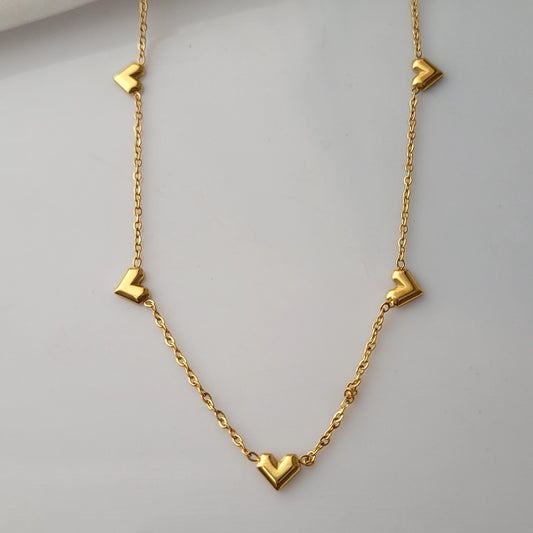 Gold necklace with heart-shaped pendants on a light gray background Goldess Jewellry with pvd plating technology which last 10 times than norlam jewelley