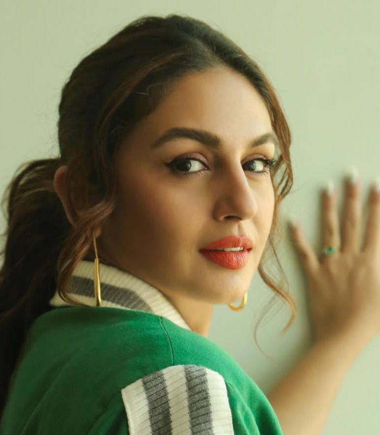Woman wearing a green outfit with a white and black striped shawl, posing against a light green background. Goldess jewellery 18k gold plated