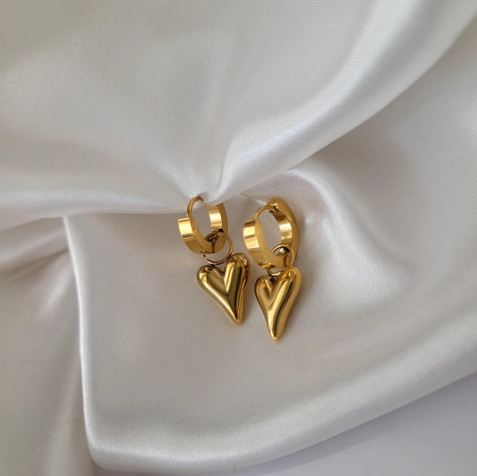 Gold heart-shaped hoop earrings on a white satin background 18k PVD gold coated