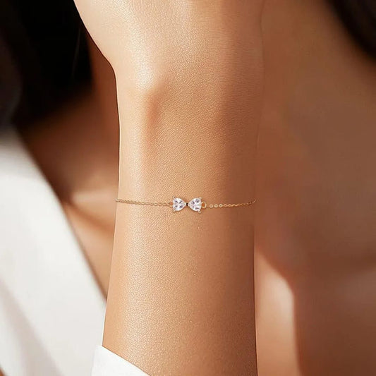 Delicate gold bracelet with heart-shaped charms on a person's wrist.goldess jewellery 18k gold plated pvd technlogy