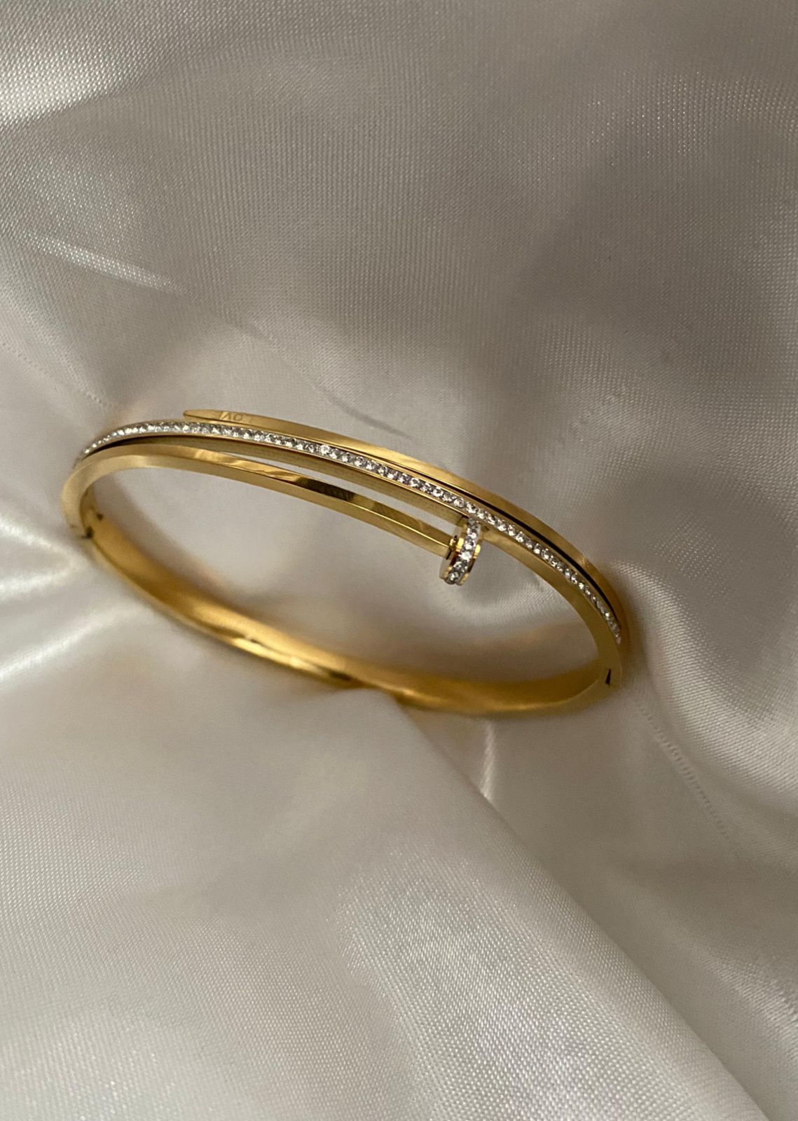 Gold bracelet with small diamonds on a light fabric background